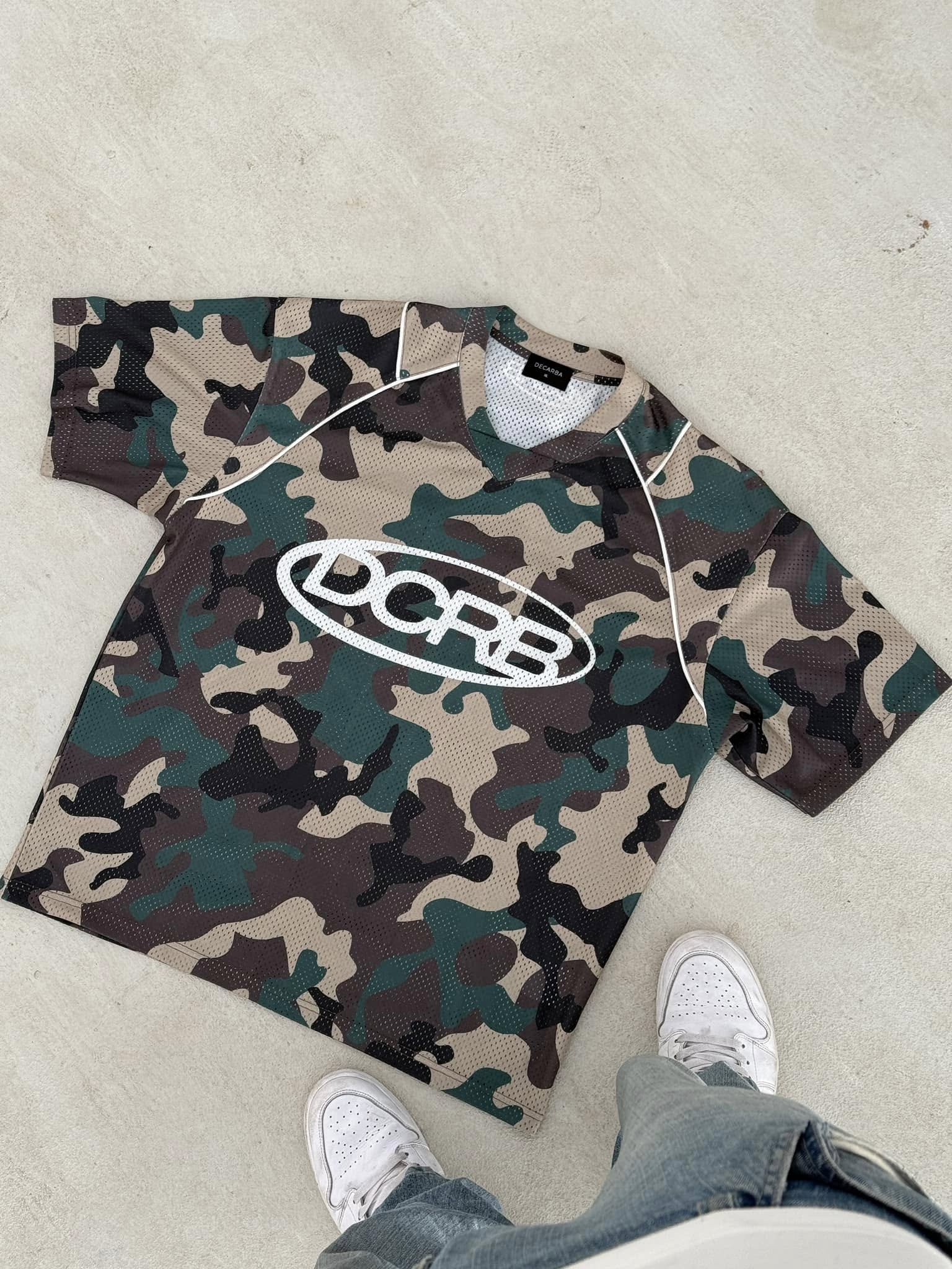DCRB camo mesh jersey with logo laid flat on concrete