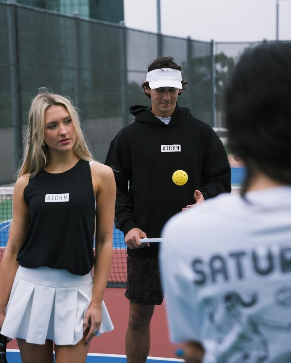 Players on a pickleball court wearing KTCHN black hoodie and tank top