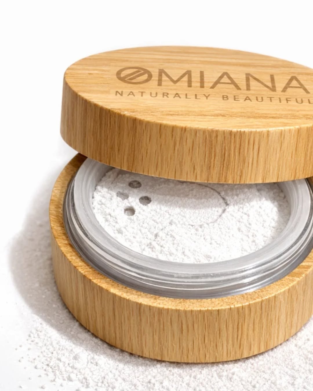 Omiana loose mineral powder in a bamboo jar with the lid resting on top