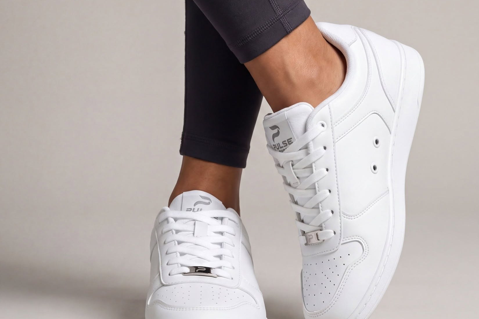 Pair of white Pulse low-top dance sneakers worn with dark leggings