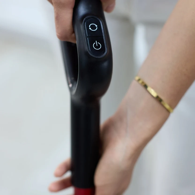 Close-up of a hand gripping the Quantum vacuum handle and power button