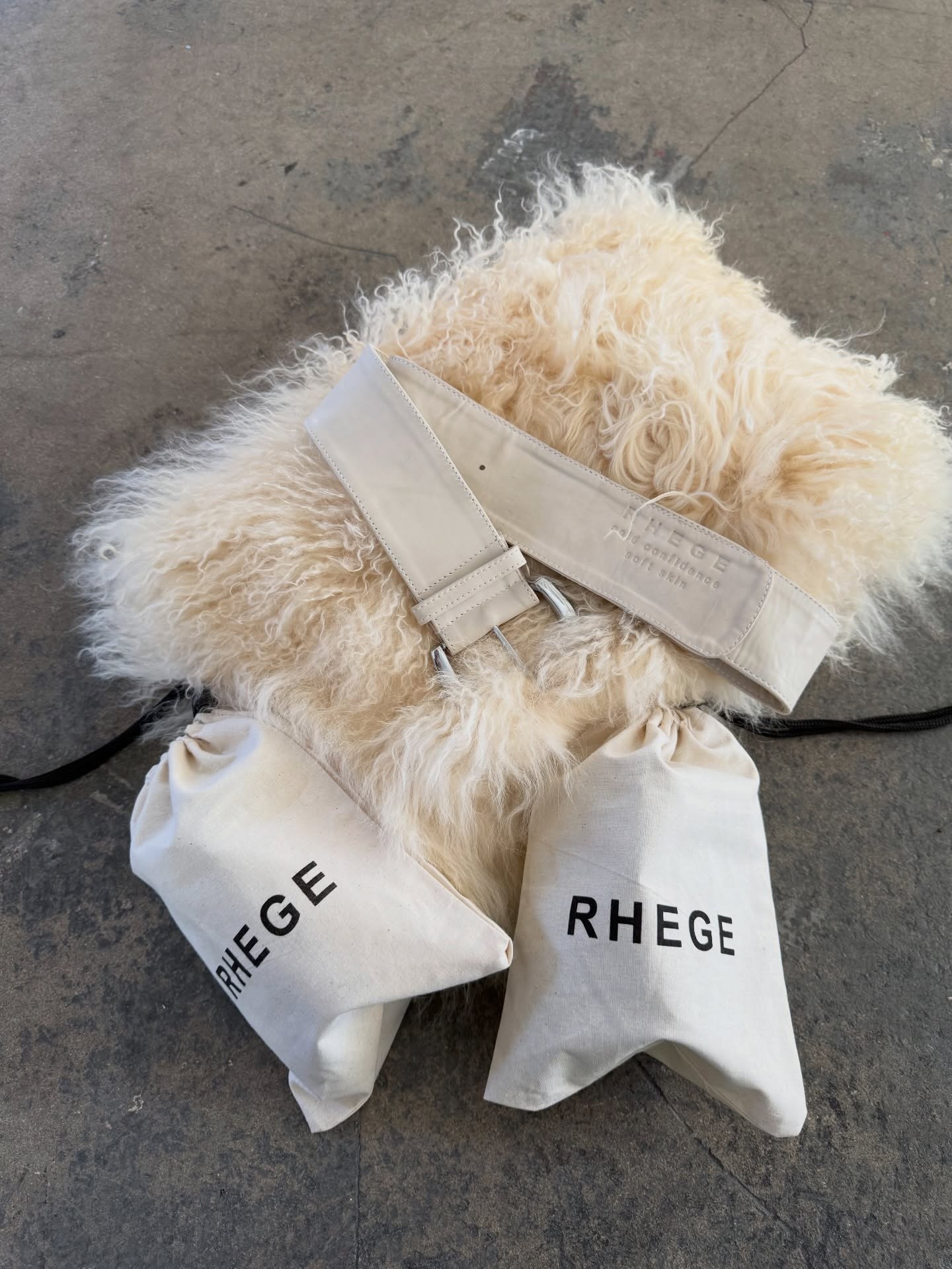 Rhege cream leather belt on a shearling piece with two Rhege cotton dust bags