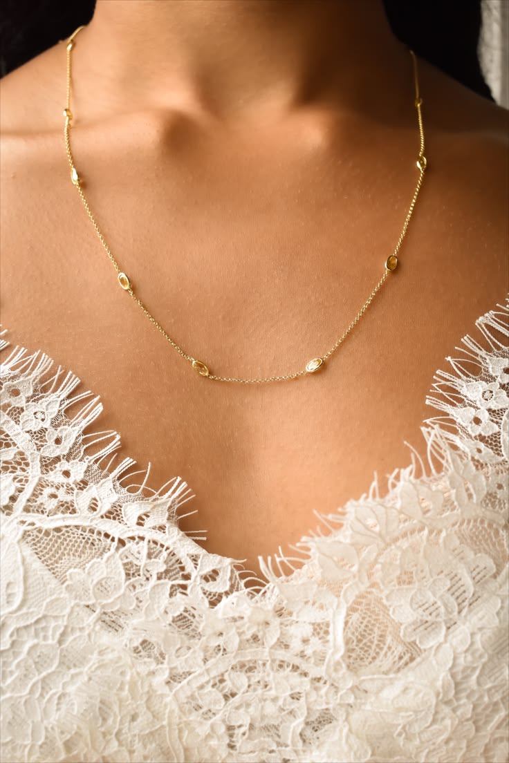 Delicate crystal station necklace layered over a lace top